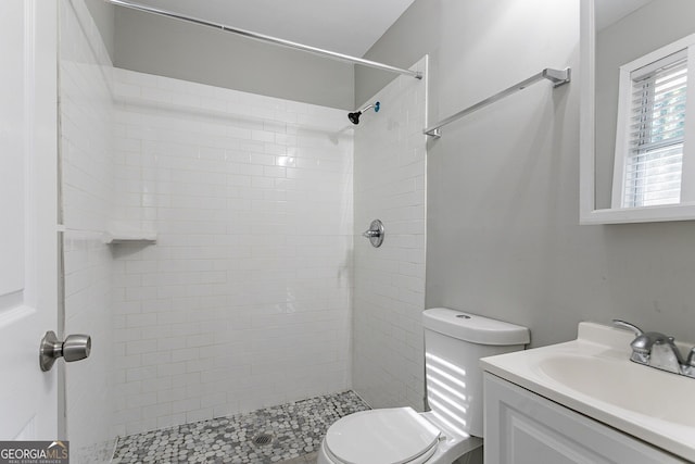 bathroom with toilet, vanity, and tiled shower