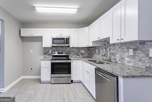 kitchen featuring sink, white cabinets, light stone counters, and appliances with stainless steel finishes