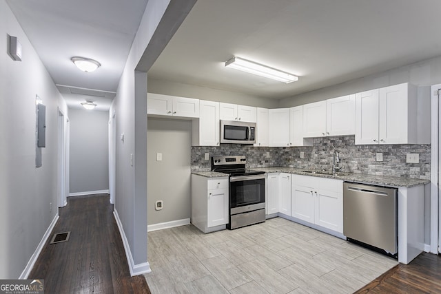 kitchen featuring stainless steel appliances, light stone countertops, white cabinets, and sink