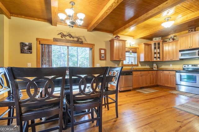 kitchen with hanging light fixtures, light wood-type flooring, appliances with stainless steel finishes, a notable chandelier, and beam ceiling