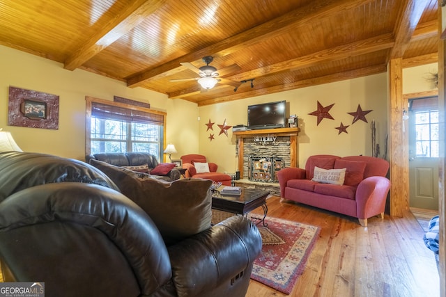 living room featuring a fireplace, wood-type flooring, a wealth of natural light, and beamed ceiling