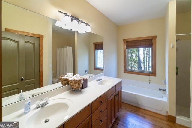 full bathroom featuring vanity, toilet, wood-type flooring, and plus walk in shower