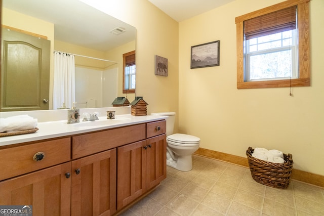 bathroom with vanity, curtained shower, toilet, and a wealth of natural light