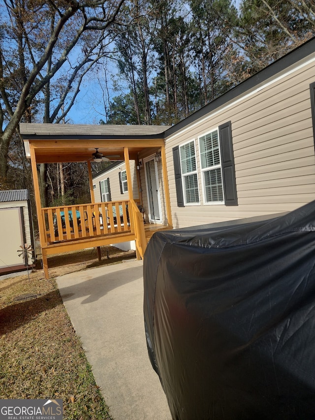 back of house with ceiling fan, a shed, and a deck