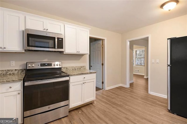 kitchen with white cabinetry, light stone countertops, light wood-type flooring, and appliances with stainless steel finishes