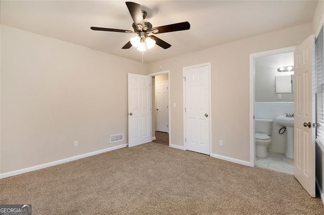 unfurnished bedroom with ensuite bath, ceiling fan, and light colored carpet