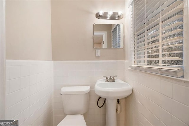 bathroom with toilet and tile walls