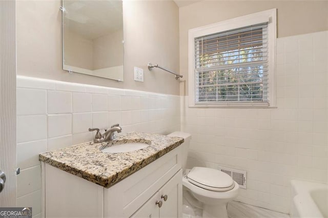 bathroom with vanity, toilet, and tile walls