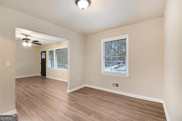 spare room featuring hardwood / wood-style floors, ceiling fan, and a wealth of natural light