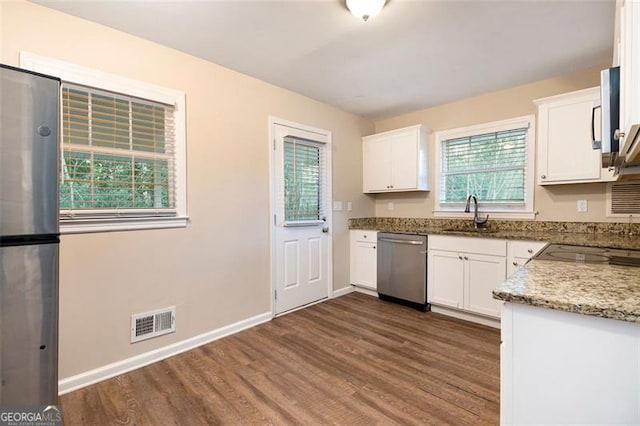 kitchen featuring dishwasher, white cabinets, light stone countertops, a wealth of natural light, and dark hardwood / wood-style flooring