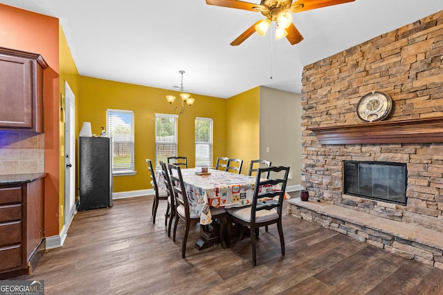 dining space featuring ceiling fan with notable chandelier, a fireplace, and dark wood-type flooring