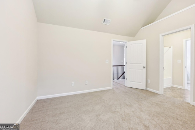 unfurnished bedroom with light colored carpet and lofted ceiling