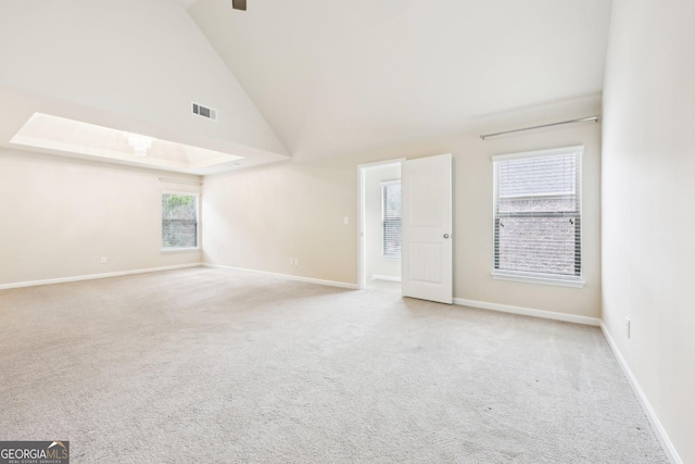 carpeted empty room with high vaulted ceiling