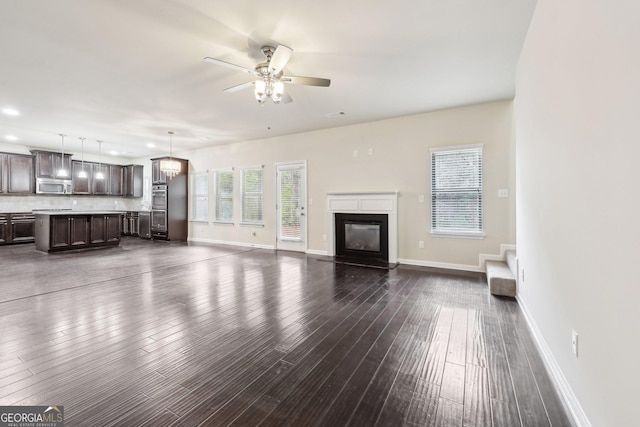 unfurnished living room with ceiling fan and dark wood-type flooring