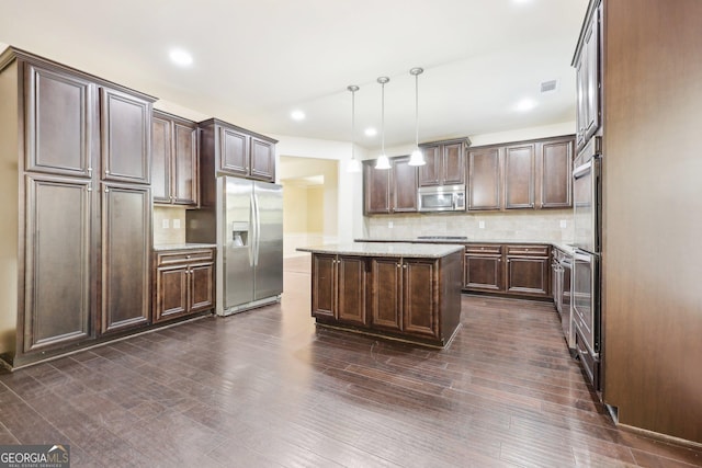 kitchen featuring tasteful backsplash, dark brown cabinets, stainless steel appliances, pendant lighting, and a center island