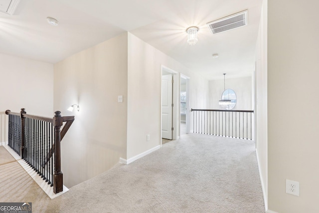 hallway with light carpet and a chandelier