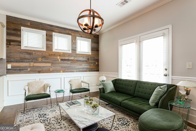 living room with an inviting chandelier, dark wood-type flooring, and crown molding