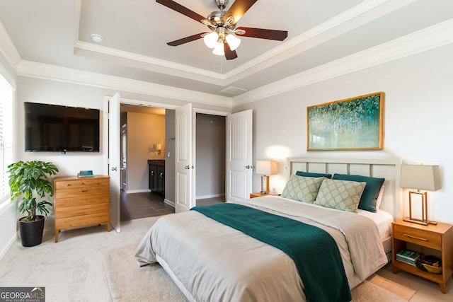 bedroom featuring a tray ceiling, ceiling fan, crown molding, and carpet floors