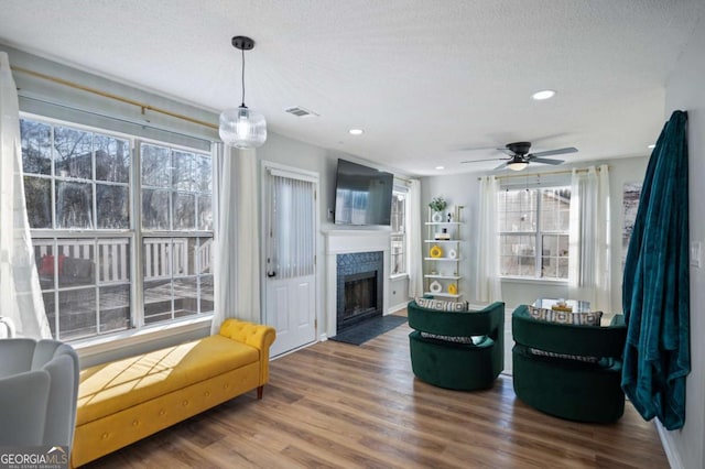 living room featuring ceiling fan, a textured ceiling, and dark wood-type flooring