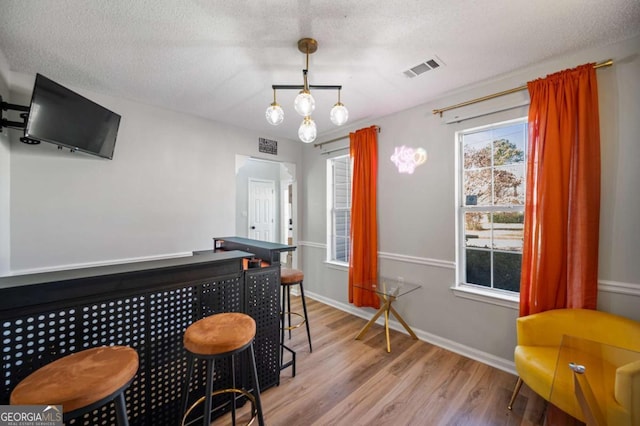 bar featuring light hardwood / wood-style flooring, pendant lighting, and a textured ceiling