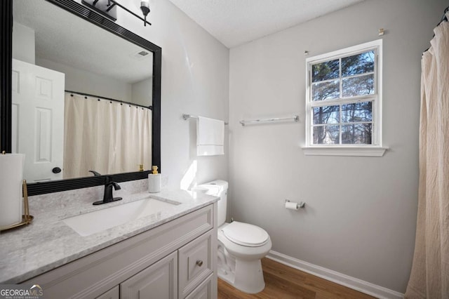 bathroom with vanity, wood-type flooring, a textured ceiling, and toilet