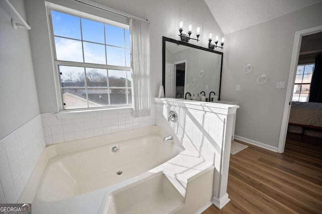 bathroom with vanity, vaulted ceiling, a textured ceiling, a tub to relax in, and wood-type flooring