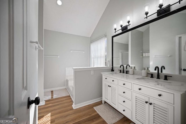 bathroom featuring a tub, vanity, wood-type flooring, and lofted ceiling