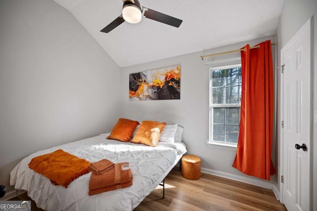 bedroom with hardwood / wood-style flooring, vaulted ceiling, and ceiling fan