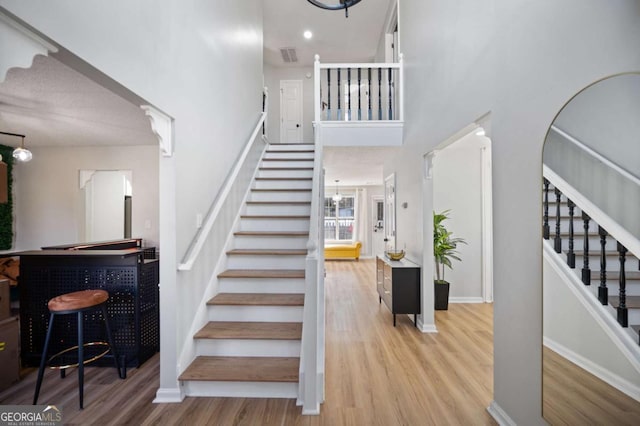 stairway with a high ceiling and hardwood / wood-style flooring