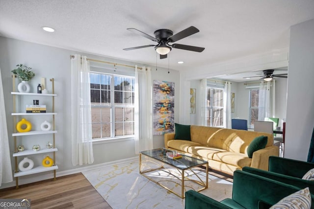 living room with hardwood / wood-style floors, ceiling fan, and a textured ceiling