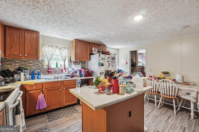 kitchen with tasteful backsplash, a textured ceiling, white appliances, sink, and a center island