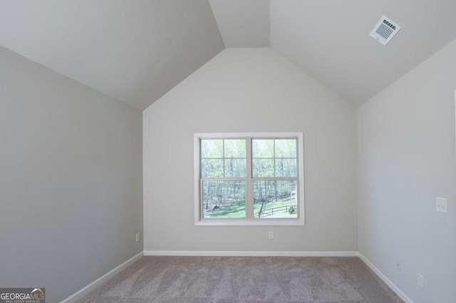 carpeted spare room featuring vaulted ceiling