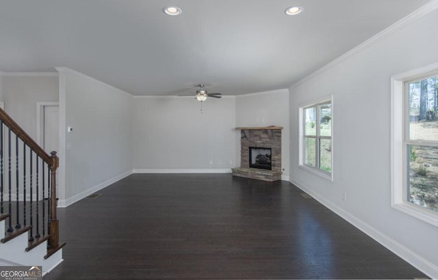 unfurnished living room featuring ornamental molding, plenty of natural light, a stone fireplace, and ceiling fan