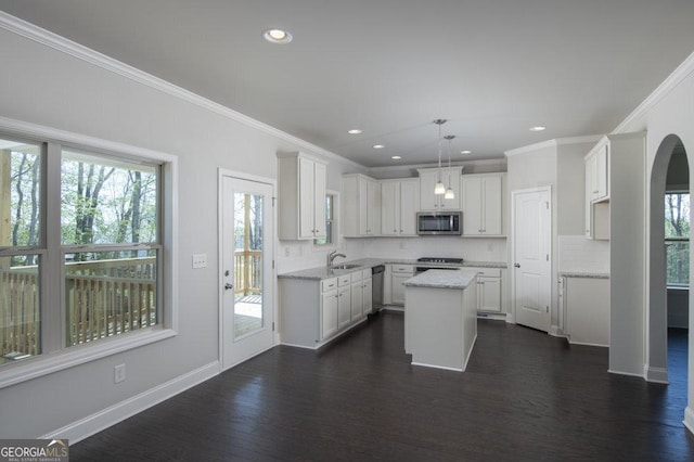 kitchen with sink, white cabinetry, stainless steel appliances, a kitchen island, and decorative backsplash