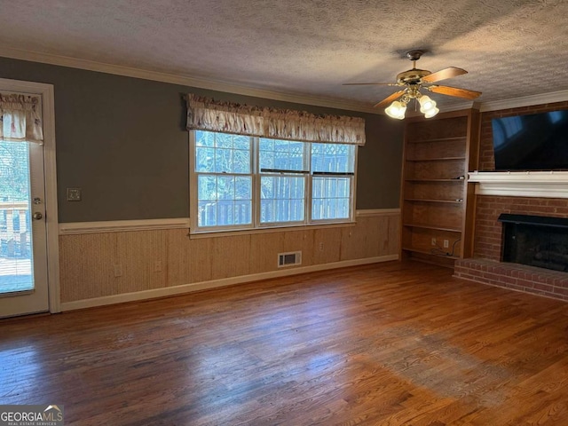 unfurnished living room featuring ceiling fan, plenty of natural light, ornamental molding, and built in shelves