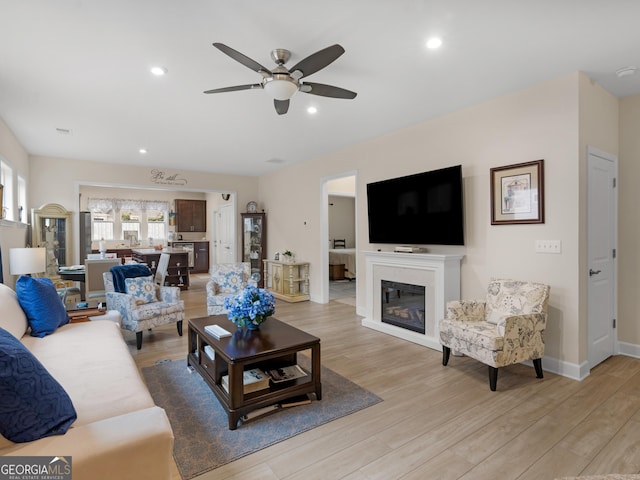 living room with ceiling fan and light hardwood / wood-style flooring