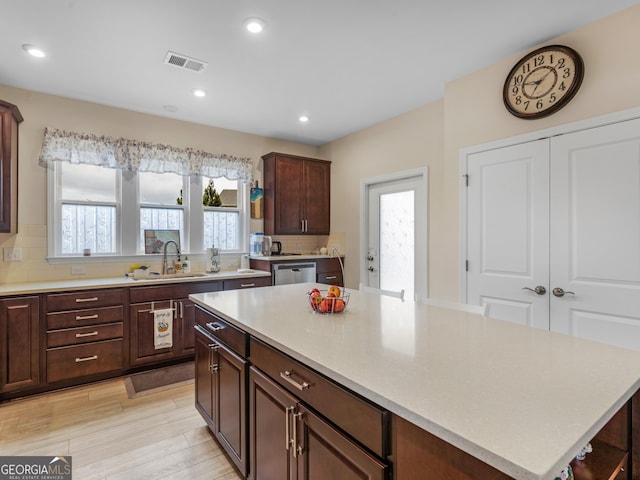 kitchen with dishwasher, sink, tasteful backsplash, light hardwood / wood-style floors, and a kitchen island