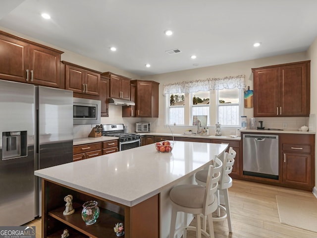 kitchen featuring backsplash, sink, a breakfast bar area, a kitchen island, and stainless steel appliances