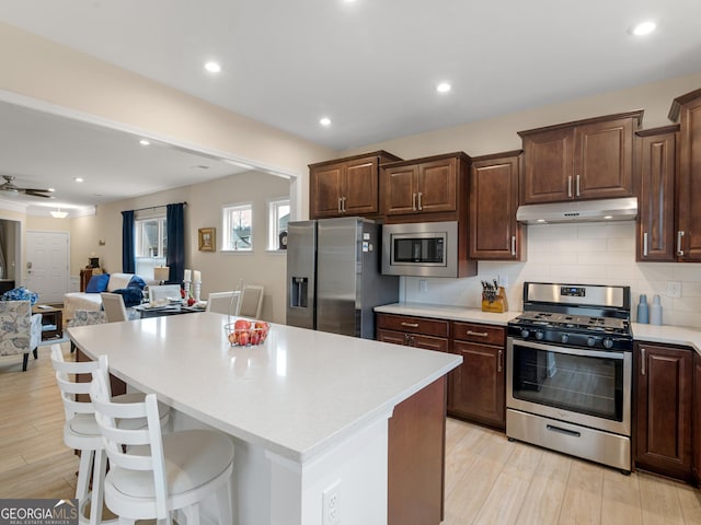kitchen with stainless steel appliances, a kitchen island, tasteful backsplash, and a breakfast bar area