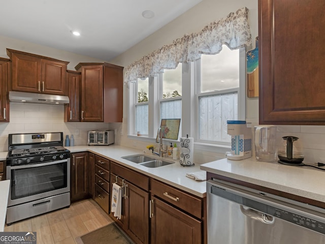 kitchen with decorative backsplash, light wood-type flooring, stainless steel appliances, and sink