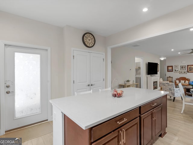 kitchen with light hardwood / wood-style floors, a kitchen island, and ceiling fan