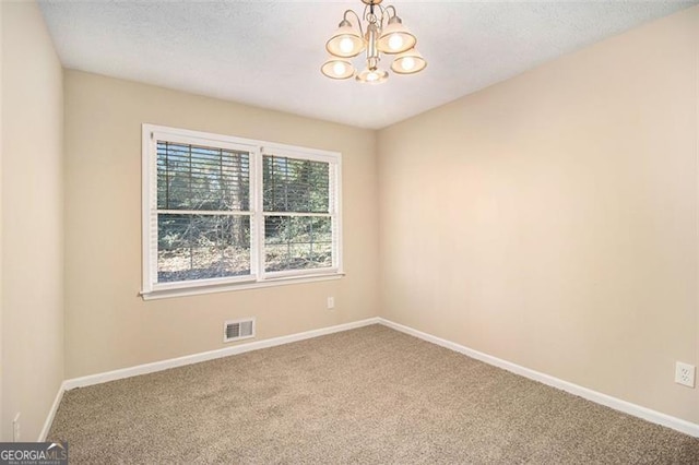 carpeted spare room with an inviting chandelier