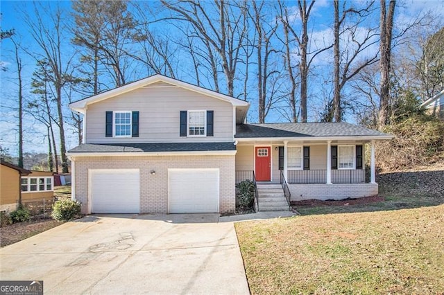 tri-level home featuring covered porch, a garage, and a front lawn