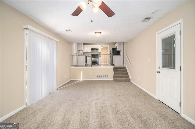 unfurnished living room featuring ceiling fan, light carpet, and a textured ceiling