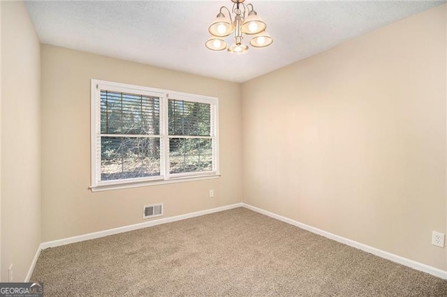 empty room with carpet floors and an inviting chandelier