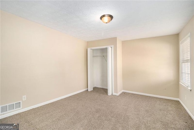 unfurnished bedroom with carpet, a textured ceiling, and a closet