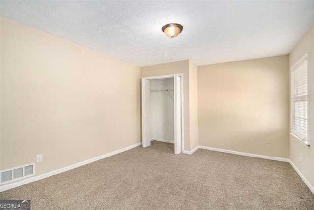 unfurnished bedroom with carpet flooring, a textured ceiling, and a closet