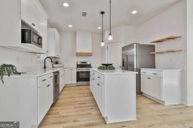 kitchen with white cabinetry, a center island, hanging light fixtures, premium range hood, and appliances with stainless steel finishes