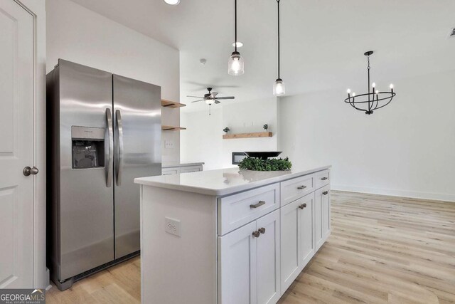 kitchen featuring a center island, white cabinets, ceiling fan with notable chandelier, stainless steel refrigerator with ice dispenser, and hanging light fixtures