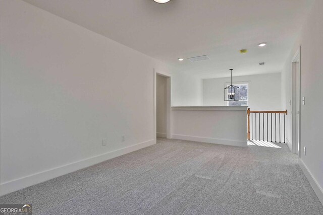 unfurnished room with carpet flooring and a chandelier